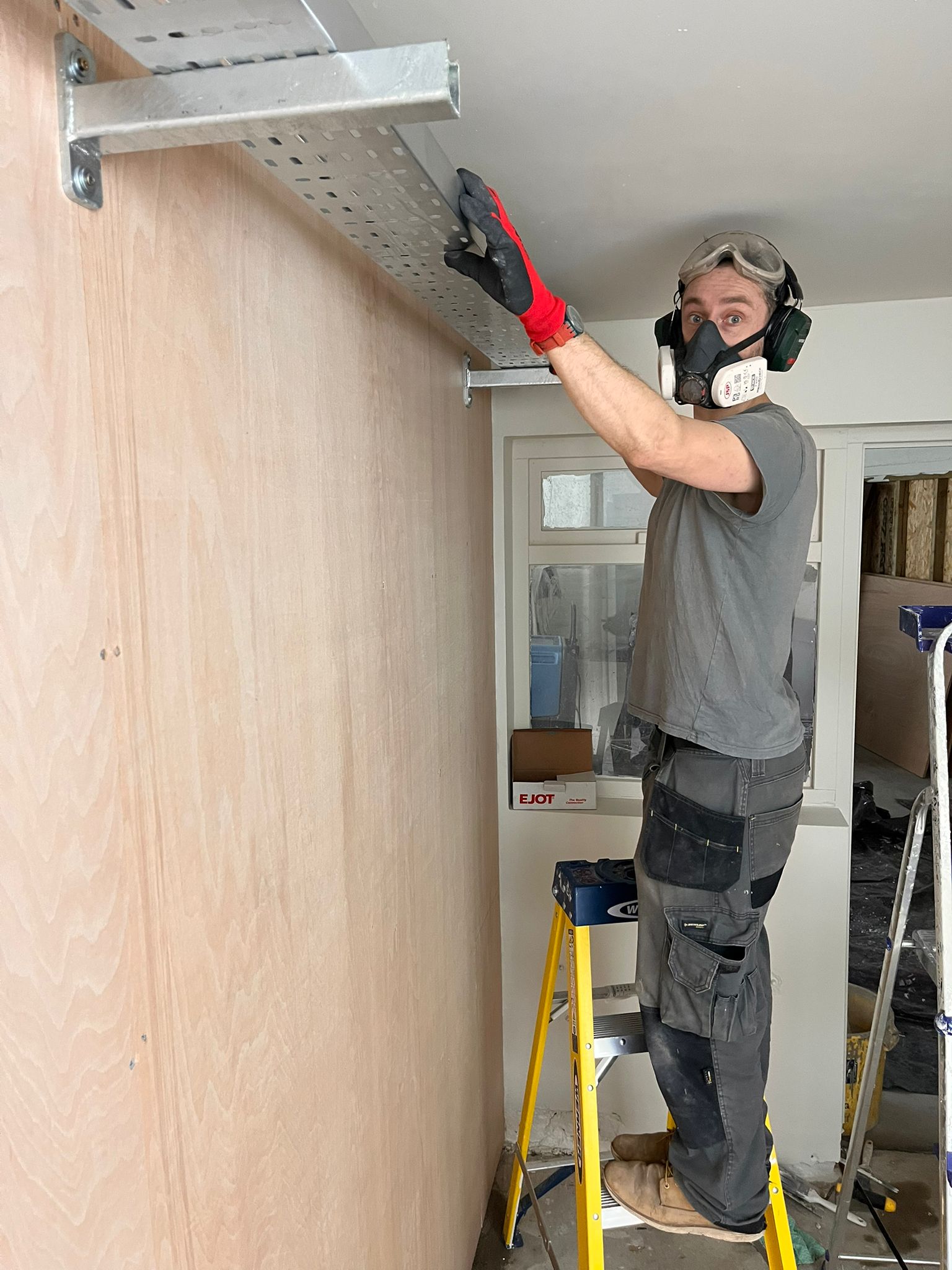 Electrician installing cable tray for commercial electrical work in North London